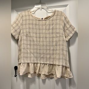 Top of shirt is a tweed material, bottom is chiffon. Size medium, but runs small